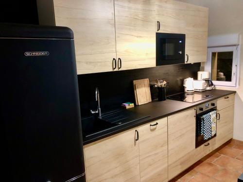 a kitchen with a black refrigerator and wooden cabinets at Domaine Plan des Devens in Roussillon