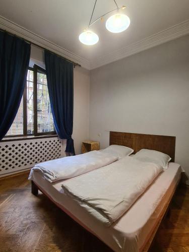 a bedroom with a large bed with blue curtains at Benevo Hostel in Tbilisi City