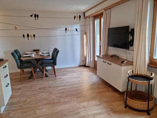 ein Wohnzimmer mit einem Esstisch und einem TV in der Unterkunft Gemütliche Ferienwohnung zwischen See und Bergen in Brienz