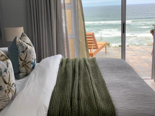 a bedroom with a bed with a view of the ocean at Mes Amis Beach Guest House in Wilderness