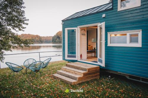 プシビツにあるPółwysep Zacisze - Tiny House Villageの青い家 階段、椅子2脚、ドア1脚