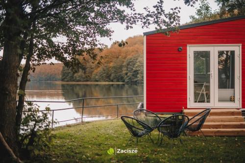 a red house with two chairs in front of it at Półwysep Zacisze - Tiny House Village in Przywidz