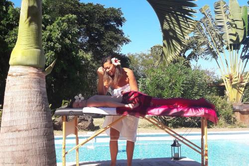 a woman sitting on a table talking on a cell phone at Villa Baies Roses in Saint-Leu