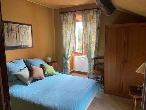 sypialnia z łóżkiem z niebieską pościelą i oknem w obiekcie Ancienne ferme Bourguignonne en bord de rivière, grand terrain arboré, et clos 