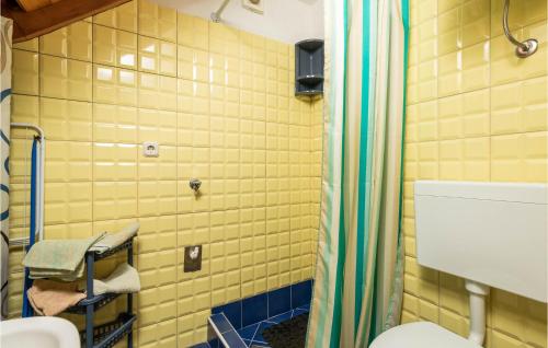 a bathroom with a toilet and a yellow tiled wall at Stunning Home In Susak With Kitchen in Susak