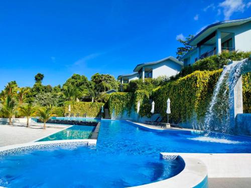a swimming pool with a waterfall in front of a house at Khaolak Blue Sky Villa in Khao Lak