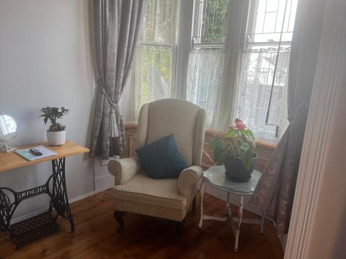 a living room with a chair and a table and windows at Heath Villa - private room in Port Elizabeth