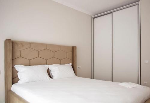 Schlafzimmer mit einem Bett mit weißer Bettwäsche und Kissen in der Unterkunft 4 Dream Apartmanet 4+parcare gratuita in Oradea