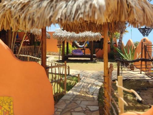 a resort with a straw umbrella and a swing at Pousada Kite Guajiru in Itarema