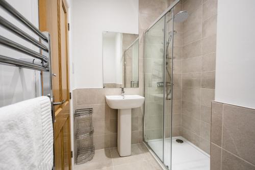 a bathroom with a sink and a glass shower at Burnside Cottage, Wark, Hexham in Hexham