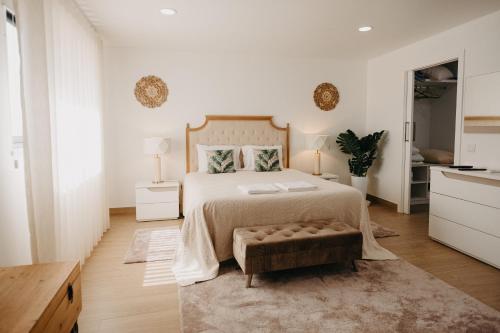 a white bedroom with a large bed and a table at Quinta Monteiro de Matos - Enoturismo in Santarém