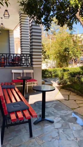 a bench and tables in a patio with a tree at Hotel Antigone in Tirana
