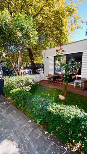 a house with a yard with a bench and trees at Hotel Antigone in Tirana