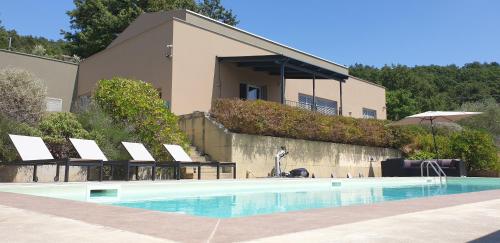 een zwembad met stoelen en een gebouw bij Moderne Villa mit atemberaubendem Seeblick in Lisciano Niccone