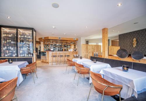 ein Restaurant mit weißen Tischen und Stühlen und eine Bar in der Unterkunft Hotel Walter in Schenna