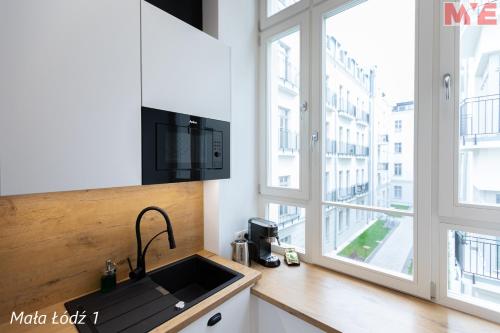 a kitchen with a sink and a large window at MYE Apartments - Kamienica Sienkiewicza in Łódź