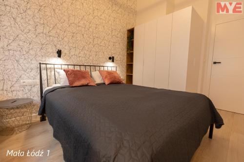 a bedroom with a bed with a black comforter at MYE Apartments - Kamienica Sienkiewicza in Łódź