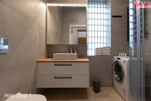 a bathroom with a sink and a washing machine at MYE Apartments - Kamienica Sienkiewicza in Łódź