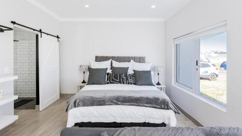a white bedroom with a large bed and a window at 34.4 Degrees South Studio Apartment in Agulhas