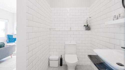 a white bathroom with a toilet and a sink at 34.4 Degrees South Studio Apartment in Agulhas