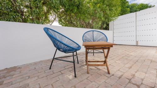 two chairs and a wooden table on a patio at 34.4 Degrees South Studio Apartment in Agulhas