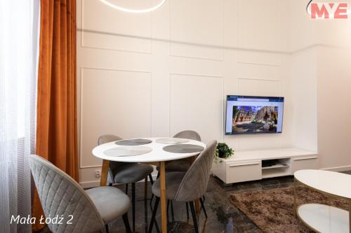 a dining room with a table and chairs and a tv at MYE Apartments - Kamienica Sienkiewicza in Łódź