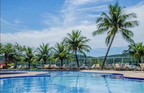 a swimming pool with palm trees and chairs at Loft 319 - INCOMPARÁVEL in Itacuruçá