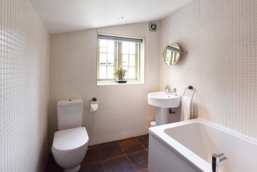 een badkamer met een toilet, een wastafel en een bad bij Fireman's Cottage in Canterbury