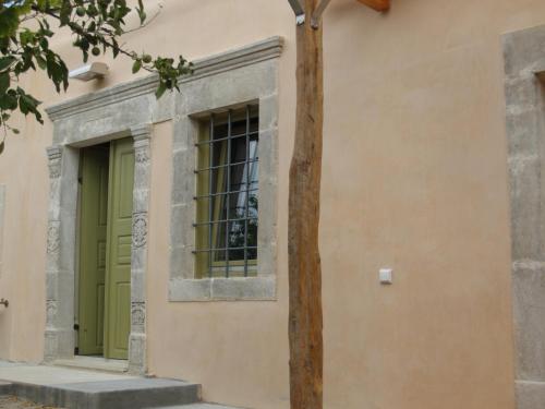 a building with a green door and a tree at Agapi Holiday House in Sívas