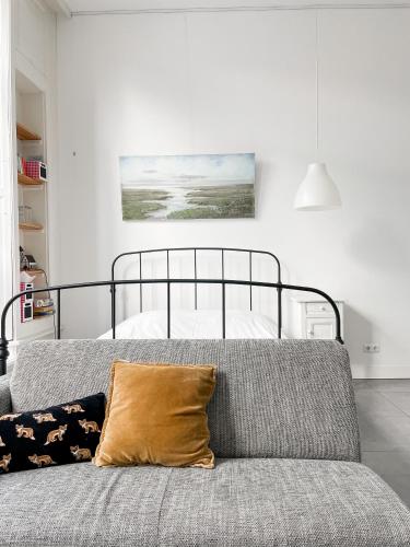 a bedroom with a bed and a couch with a pillow at Gastenverblijf De Oare Keamer Kollum Friesland in Kollum
