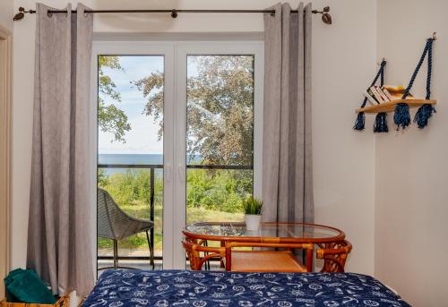 a bedroom with a table and a large window at Apartament z widokiem na morze U Grażyny 2 in Jarosławiec