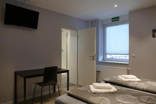 a room with two beds and a desk and a television at Pension Sölde UG in Dortmund