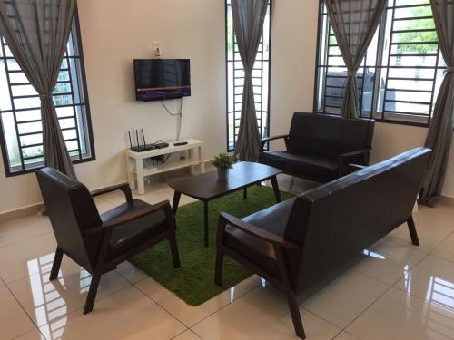 a living room with a couch and chairs and a tv at Casuarina Sea Breeze Desaru in Desaru