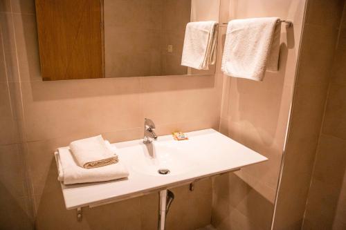 ein Badezimmer mit einem Waschbecken, einem Spiegel und Handtüchern in der Unterkunft Sahara Line Hotel in El Aaiún