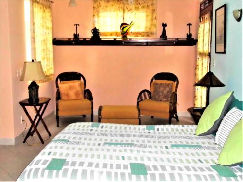 a bedroom with two chairs and a bed with a bedspread at Casa Gatos in Akumal