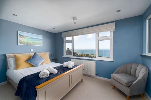a bedroom with blue walls and a bed and a chair at Porthmeor View in St Ives