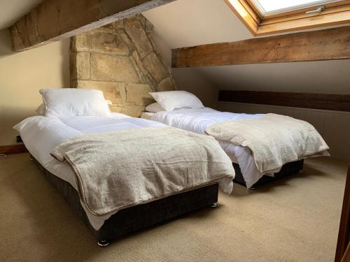 two beds in a bedroom with a stone wall at Meg's Den in Hebden Bridge
