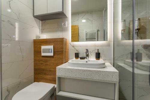 a white bathroom with a sink and a toilet at Golden Pine, a private apartment in five star hotel in Zlatibor