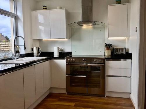 uma cozinha com armários brancos e um forno de aço inoxidável em Kelvinside, Seahouses, 2 minute walk into village em Seahouses