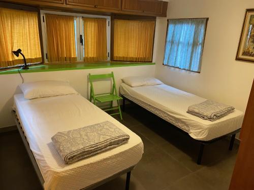 a room with two beds and a green chair at Camping Roma in Ventimiglia