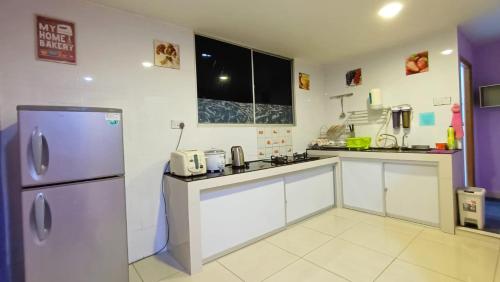 una cocina con nevera de acero inoxidable y armarios blancos en Taman Tunku Miri Budget Homestay, en Miri