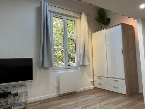 a living room with a television and a large window at Paris : charmant 2 pièces au calme in Paris