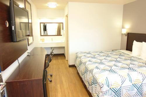 una habitación de hotel con una cama y un televisor en Motel 6 Hattiesburg, MS, en Hattiesburg