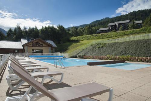 een zwembad met 2 lounges en een avisorvisor bij Résidence La Marmottane in Aime