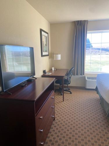 a hotel room with a desk and a television and a bed at Cobblestone Hotel & Suites - Broken Bow in Broken Bow