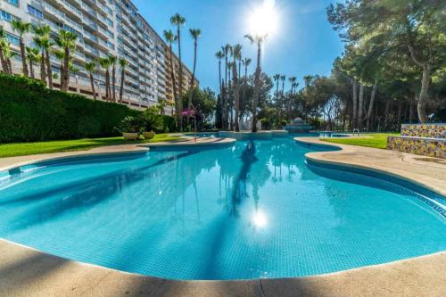 a swimming pool at a resort with palm trees and a building at Apartamento Ines, Dehesa de Campoamor,900m from the sea , swimming pool & tennis court in Campoamor