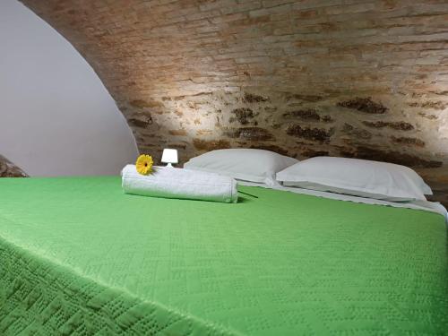 a bed with a green blanket and a yellow flower on it at Matalena in Pomarico
