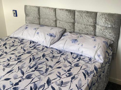 Una cama con dos almohadas con flores azules. en Loving Home to Stay with Rear Garden and Patio, en Rochdale