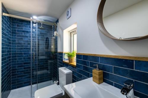 a blue tiled bathroom with a toilet and a mirror at Chi Lowarth in Helston