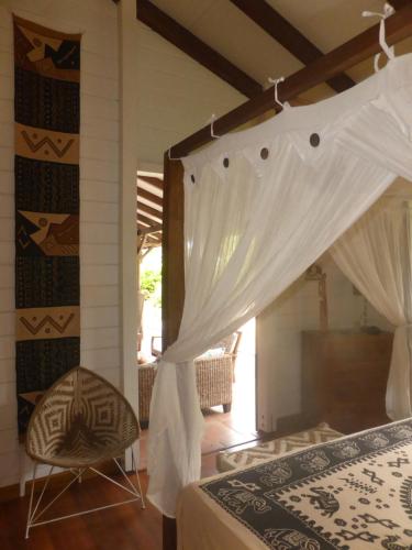 a bedroom with a bed with curtains and a chair at Caribbean Ashanti Lodge in Trois-Rivières